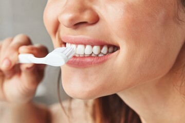 Fototapeta premium A close-up of a person brushing their teeth with a white toothbrush, focusing on clean, healthy teeth and oral hygiene.