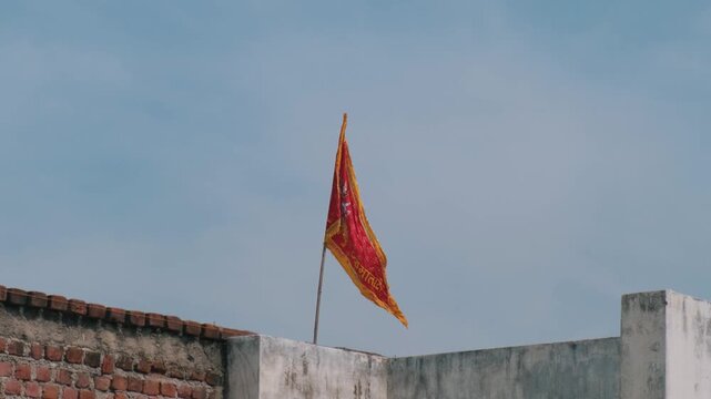 Saffron Hindu religious flag with Jai Mata Di text waving on a rooftop against a clear sky