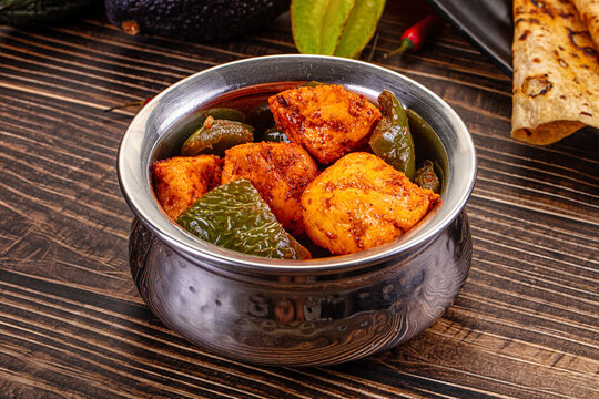 Indian Paneer Tikka Masala inl with Roti bread on a dark wooden table