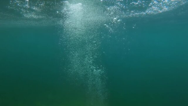 Underwater air bubbles rising toward the surface in this crystal clear blue ocean water creates a beautiful motion footage for your nature projects