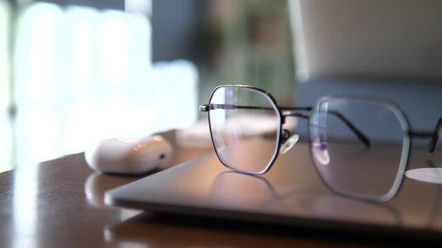Vertical close-up of blue light blocking glasses on a digital tablet with a blurred young girl studying in the background, education and digital eye strain concept