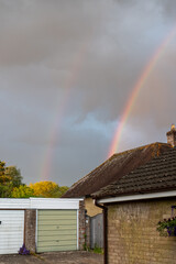 Naklejka premium A bright, colorful rainbow arcing across a dramatic cloudy sky after a rainstorm.