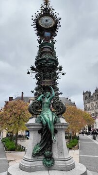 Vertical slow tilt-up of the intricate Jules Verne Clock in Amiens under a cloudy sky.