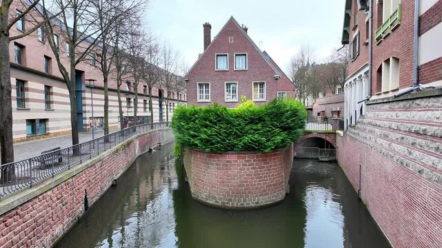 Static wide shot of a charming brick house situated at the fork of a canal.
