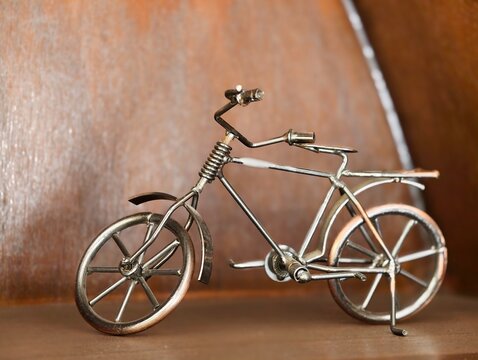 Handcrafted vintage metal bicycle miniature model featuring a rustic bronze finish and intricate welding details, isolated on a textured wooden background