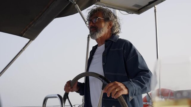 Mature captain steering sailboat at sea