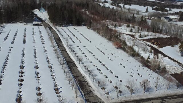 This aerial winter scene captures Lac‑au‑Saumon&rsquo;s snowy cemetery alignment leading to Saint Joseph&rsquo;s Oratory and the historic convent, highlighting the village&rsquo;s architecture and quiet seasonal beauty