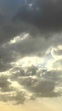A captivating, fast-paced time-lapse video capturing dramatic, fluffy white cumulus clouds sweeping rapidly across a clear blue sky. The camera is oriented directly upward, providing an immersive, swe