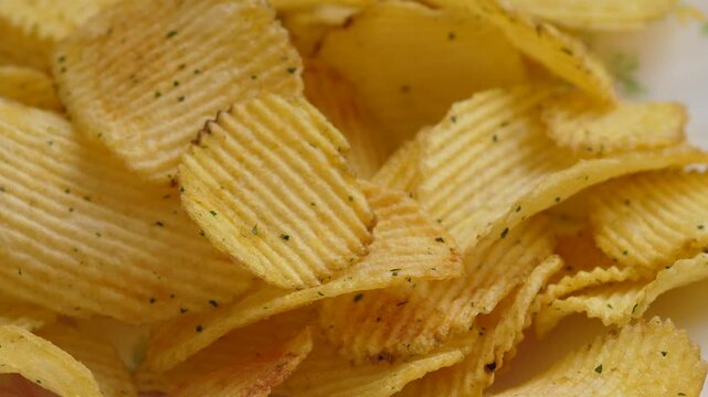 Close-up of golden ridged potato chips with sour cream and onion seasoning. Crunchy salty snack with prominent texture captured in macro for food advertising