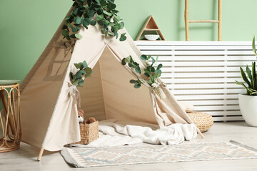 Cute wigwam with leaves and blanket in stylish child's room © New Africa