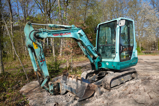 Ein t&uuml;rkisfarbener Takeuchi Minibagger Modell TB 228 an einem Waldrand