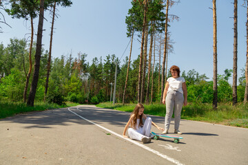 Active happy grandmother and granddaughters having fun time together skateboard in the forest. © Mariia