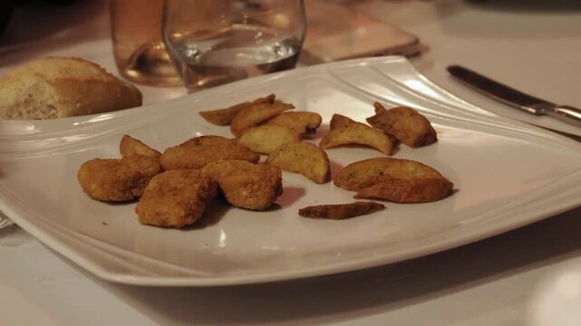 Nuggets de poulet et pommes de terre r&ocirc;ties servis dans une assiette en restaurant ambiance conviviale