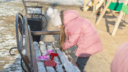 little girl playing on the playground on a winter day © Mariia