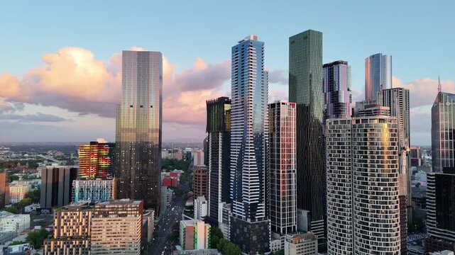 Smooth drone pan across Melbourne CBD skyline with modern skyscrapers under clear blue sky during golden hour. Scenic aerial city view in Melbourne, Australia.