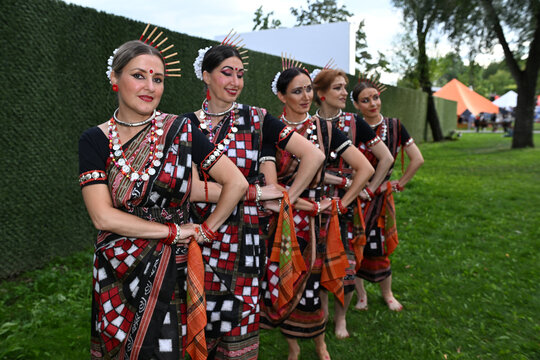 Five female dancers in colorful costumes dancing Indian dances in the park