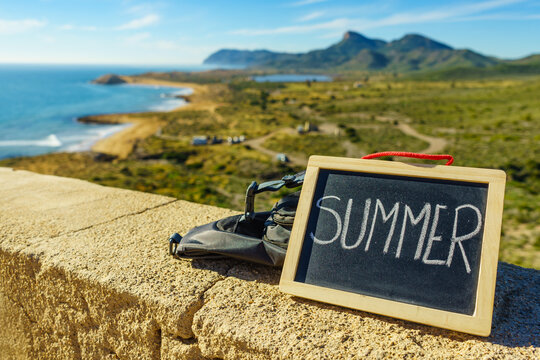 Black board with word summer against sea coast