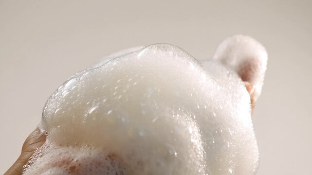 Thick white soap foam runs down a human hand