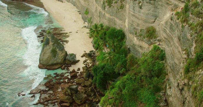 Tropical Diamond beach with white sand and turquoise water with high limestone cliffs in Nusa Penida