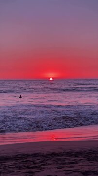Stunning sunset over ocean horizon in Goa with red and purple tones gentle surf and reflective shoreline