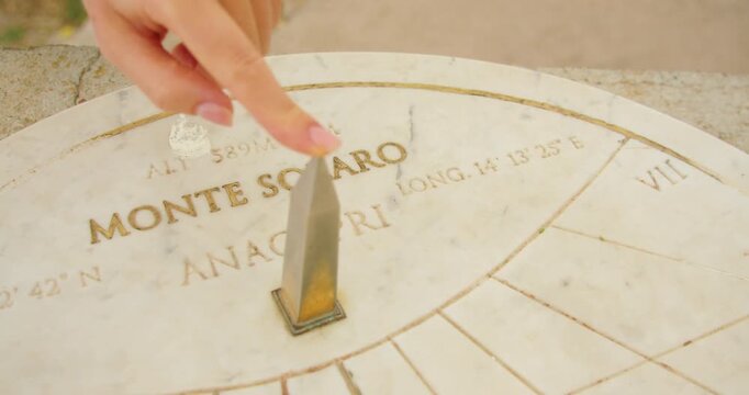 A visitor points to a sundial at Monte Solaro in Capri during a clear and warm summer day
