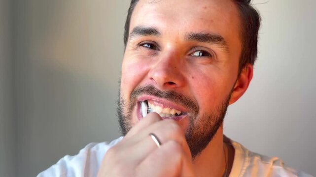 Adult man brushing teeth with electric toothbrush at home, healthy lifestyle, dental care, morning routine.