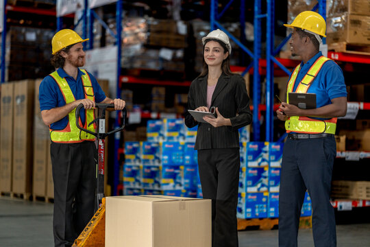 Warehouse management team supervising operations in an industrial facility. Diverse staff in safety gear utilizing digital tools for inventory accuracy and logistics workflow optimization.
