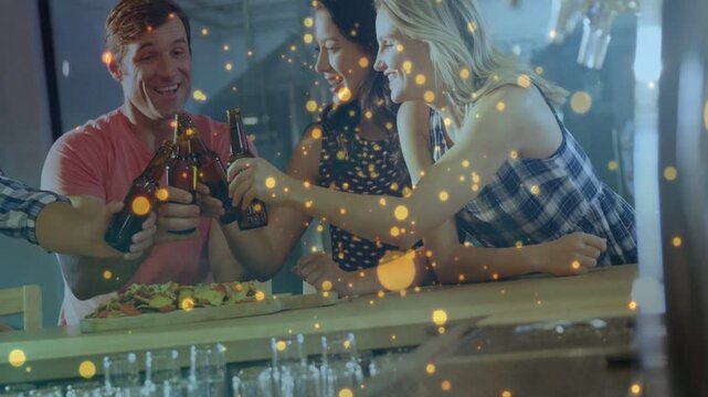 Friends gathering at counter, left arm adding bottle, toasting beers under golden bokeh bar