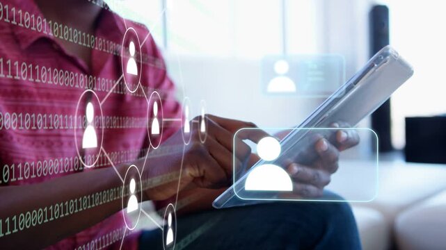 Adult African American man in red shirt sitting on sofa at home tapping tablet, scrolling overlays