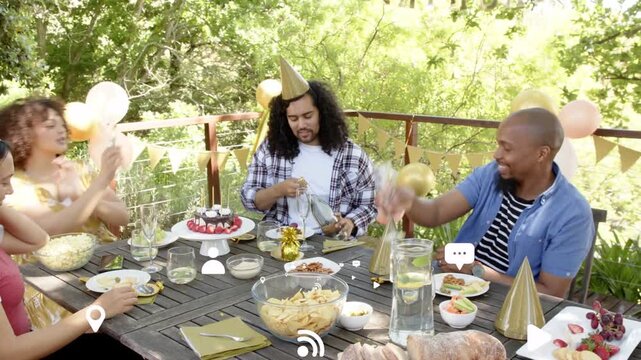 Grabbing bottle, center guest popping cork, then adjusting gold balloon while friends celebrating