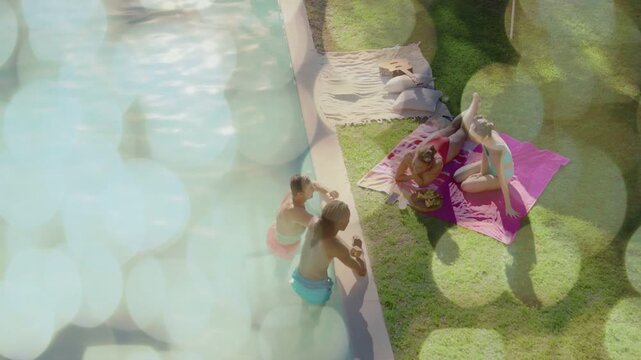 4 friends poolside socializing, man lifting drink sharing snacks, bokeh drifting over pool for ads