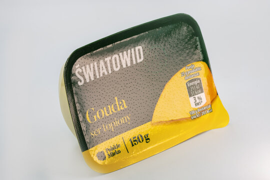 Processed gouda cheese spread in plastic container closeup on white.