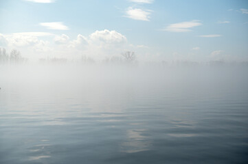 Fototapeta premium Morning fog on the river in spring. Blue sky with clouds.