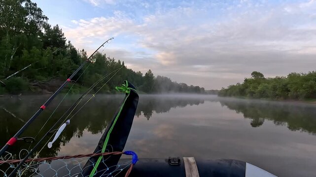 Calm river mist rises gently in early morning light. Fishing rods rest securely in a small boat. Trees frame the peaceful, reflective waters. Silent stillness suggests patience, quiet anticipation