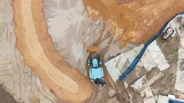 Heavy machinery moves earth in a vast excavation site. Progress through soil and rock. No people are visible, so no emotions are shown. Ideal for construction, mining. No animals or plants are present