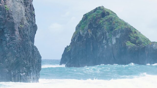 Rough ocean waves crashing against rocky cliffs and sea stack