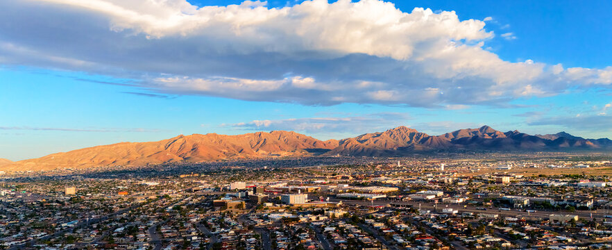 Aerial view of El Paso city skyline with desert mountains and dramatic clouds