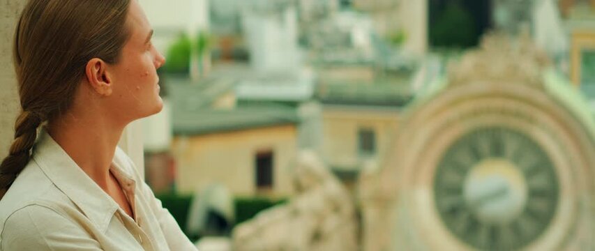 Woman looks thoughtfully at Milan skyline from Duomo rooftop terrace overlooking European cityscape in summer