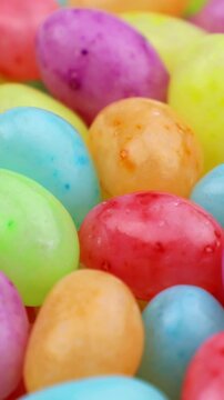 Many colorful fruit jelly beans falling down close up, vertical video