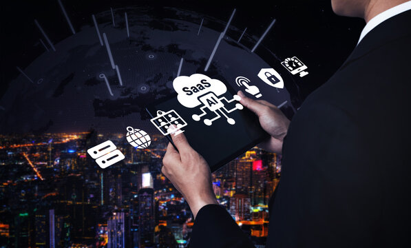 A businessman engages with a tablet displaying AI and SaaS icons against a stunning digital cityscape, showcasing the fusion of technology and modern business solutions. Ledger