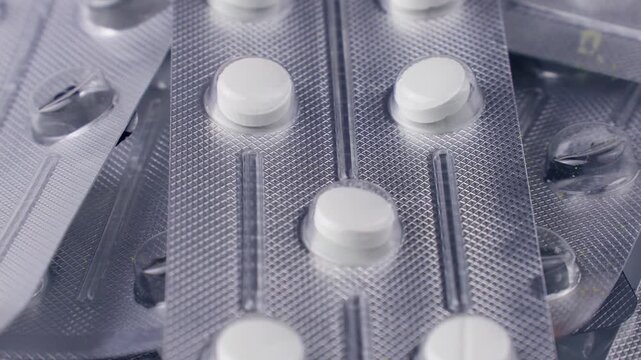 Medicine blister packs with pills circle rotation close up. Sterile medicinal tablets in protective packaging.