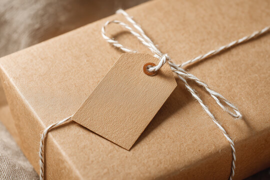 Gift wrapped box with a tag tied with twine placed on a neutral background