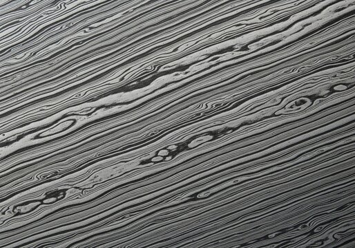 Close up texture of damascus steel surface with abstract wavy folded metallic lines pattern