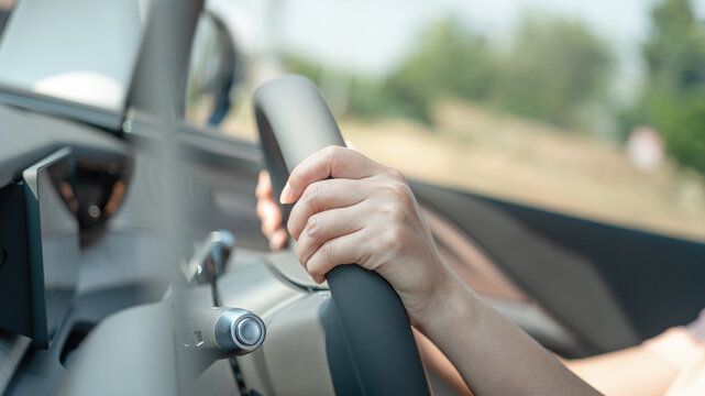 Action of a driver is gripping on steering wheel to control the car during driving. Transportation mode with close-up and selective focus on the hand.