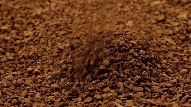 Brown instant freeze-dried coffee grains falling down close up