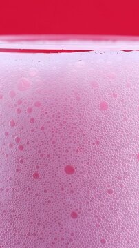 Bright pink foamy fruit cherry beer in the glass close up, vertical video format