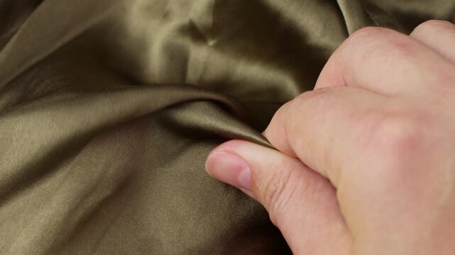 Female hands touching olive green color natural silk fabric close up