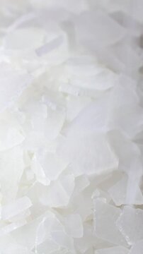 Magnesium Chloride flakes or Bischofite (Magnesium Bath Salt) falling down close up, vertical video format