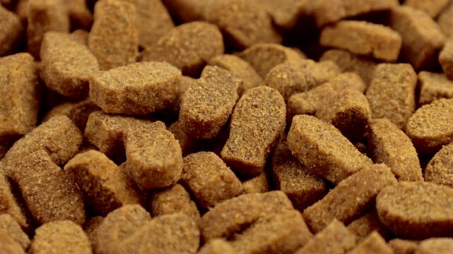 Brown kibble pieces of dry fish cat food circle rotation close up