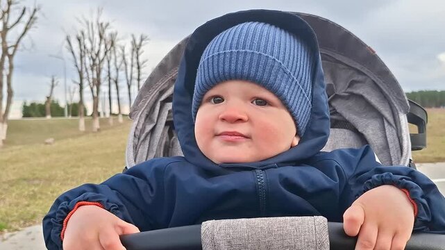 Adorable toddler boy in stroller enjoying fresh air outdoors